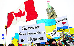 People wave Canadian and Ukranian national flags during a rally to express solidarity with anti-government protesters in Ukraine, on Parliament Hill in Ottawa on Thursday