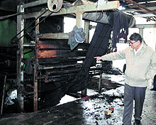 Owner of a blanket-manufacturing unit shows a machine that caught fire in Amritsar on Friday