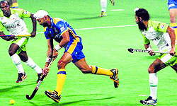 Sandeep Singh dribbles past the Delhi Waveriders players, in New Delhi on Friday