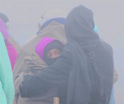 A woman wraps her child with a shawl to protect him from cold on a foggy morning in Amritsar on Saturday.