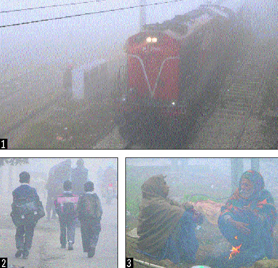 A train runs engulfed in fog at Amritsar railway station on Saturday; amidst dense fog ,children on their way to schools in Amritsar; people sit near a bonfire to keep themselves warm on a chilly day.