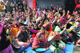 AIE/EGS teachers sit on a dharna below the water tank atop which teachers had climbed on Sunday