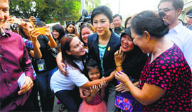 Thai Prime Minister Yingluck Shinawatra (centre) is greeted as she arrives at a polling station to cast her vote in Bangkok on Sunday.