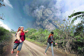 People run away from hot ash clouds engulfing villages in the vicinity of Mt Sinabung volcano in Indonesia on Sunday. Sixteen people have died from lava and ash spewed by the volcano.