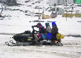 Tourists enjoy a ride on a snowmobile in the Solang valley on Monday