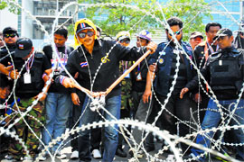 Anti-government protesters cut a barbwire fence at a government office where Prime Minster Yingluck Shinawatra had been holding a meeting in Bangkok on Monday.