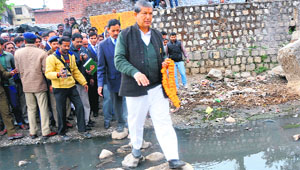 Chief Minister Harish Rawat crosses a nullah during a visit to a slum in Dehradun on Tuesday.