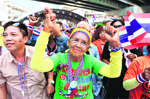 Anti-government protesters react to a leader's speech during a rally at a protest site in Bangkok on Tuesday.