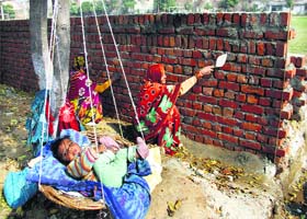 Mothers care: Women work at a construction site as their baby enjoys a handmade swing in Jalandhar