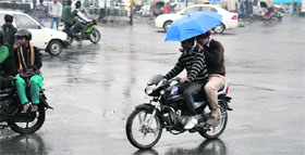 Two motorcyclists try to protect themselves with an umbrella from the rain that drenched Bathinda on Thursday.