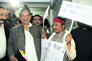 Dilip Rawat, BJP legislator, holding placards demands relaxation in forest laws while Chief Minister Harish Rawat walks past him in the state Assembly in Dehradun on Thursday.