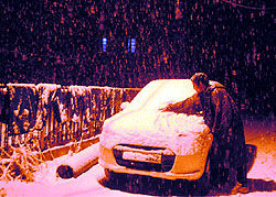 A youth clears snow from his car in Srinagar. The Valley received fresh snowfall last evening