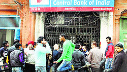 People gather outside the bank after the accidental firing by a guard in Jalandhar on Saturday