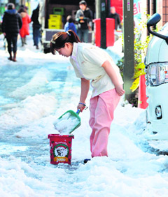 A woman shovels snow on the street in Tokyo on Sunday.