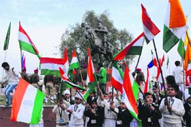 Schoolchildren wave national flags to pay tributes at the memorial of the legendary Sikh warrior, General Sham Singh Attari, at the India Gate, in Amritsar on Monday