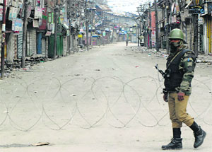 A CRPF personnel patrols a deserted street on the second day of restrictions in Srinagar on Monday. 