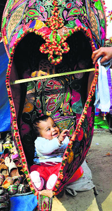 A toddler frolics in a large-sized shoe at the Surajkund International Crafts Mela in Faridabad on Tuesday.