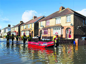 Rescue workers walk down a flooded street in Egham on Tuesday. Driven by the wettest winter since 1766, the floods first hit England about seven weeks ago. British PM David Cameron cancelled a planned visit to Israel next week to deal with floods