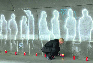 A man lights candles where revellers died during Love Parade techno festival in Duisburg. German prosecutors on Tuesday said they would reopen the case in which 21 people were killed in a stampede in 2010