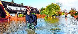 A man crosses a flooded street in Wraysbury, west of London, on Wednesday