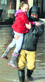 A man carries his daughter through floodwaters in Worcester, England, on Thursday after the Severn river broke its banks.  AFP