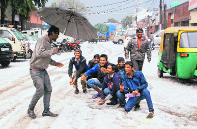 Youth enjoy the white look of a road at Industrial Area, Phase-I, after hailstorm in Chandigarh on Saturday.