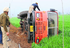 A policeman rescues a firefighter who got stuck in a fire tender after it overturned in a field at Chappar Chiri village in Mohali during rain on Saturday.