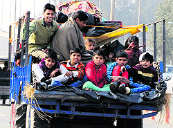 Children enjoy a risky ride on a tractor-trolley on a city road. The use of transport vehicles for ferrying passengers is illegal