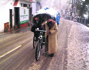 A rickshaw-puller faces a tough time amid hail and snow in Mussoorie on Sunday