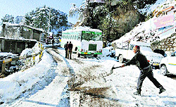PWD workers clear a snow-covered road in Shimla on Sunday