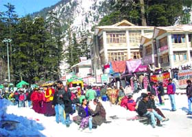 Tourists and local residents walk on the snow-covered Mall Road in Manali on Monday