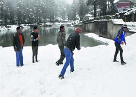 Tourists enjoy fresh snowfall at Naddi near Dharamsala on Monday