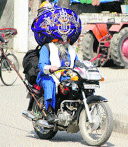 Nihang Avtar Singh Moni from Hazur Sahib travels towards Kartarpur on his bike, donning 645 m long and 85 kg headgear, in Jalandhar on Monday.