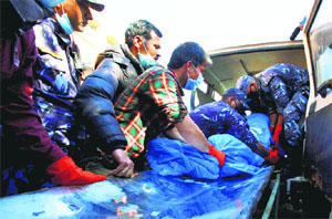Hospital officials and Nepalese police officers carry the remains of a plane crash victim out from an ambulance upon arrival at a hospital in Kathmandu on Monday