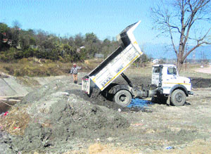 A tipper of the BBMB dumps silt on the banks of the Suketi khud at Sundernagar.