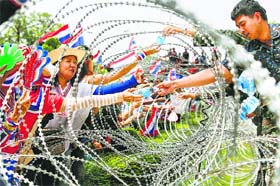 Thai soldiers hand out bottles of water to protesters through a barbed-wire fence in Bangkok on Wednesday