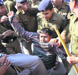 Policemen whisk away a shiksha mitr protesting near the Vidhan Sabha in Dehradun on Thursday.