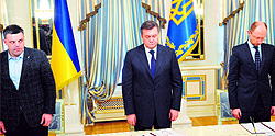 Svoboda party head Oleh Tyagnybok, Ukrainian President Viktor Yanukovych, and the Batkivcshchyna party head Arseniy Yatsenyuk pay homage to people who died during clashes in Kiev before signing an agreement on Friday
