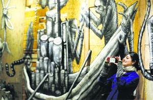 A visitor photographs artist Phlegm’s art installation “The Bestiary” at the Howard Griffin Gallery in London.