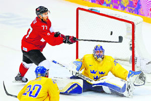 Canada's Jeff Carter tries to hit a bouncing puck past Sweden's goalie Henrik Lundqvist (R) as Sweden's Alexander Steen looks on during the third period of their men's ice hockey gold medal match at the Sochi Olympic.
