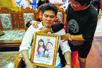 Thayakorn Yosubon, the father of siblings killed in Sundays blast, mourns as he holds a photograph of the children during their funeral at a Buddhist temple in Bangkok on Monday.  Reuters