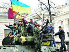 Protesters wave a Ukranian flag atop a Ukranian army armoured personnel carrier outside the Parliament building in Kiev.