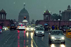 Vehicles plying during the rain at Vijay Chowk in New Delhi on Friday