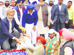 Minister for Food and Civil Supplies Adesh Partap Singh Kairon distribute a blue card to a beneficiary of the Atta-Dal Scheme in Fatehgarh Sahib on Friday. Tribune photo