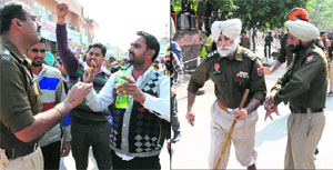 A policeman pacifies a protester holding a petrol bottle; and (right) DSP Gurjit Singh Romana chases the protesters in Bathinda on Sunday. 