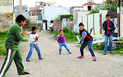 Children play cricket on a street in Ludhiana