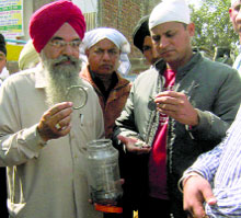 Volunteers show items recovered from Kalianwala Khuh in Ajnala on Sunday.