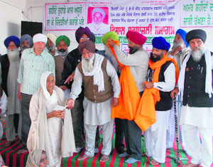 A farmer gives a relief cheque to deceaseds wife Amar Kaur