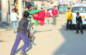 Children play cricket on a street