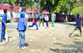 Youngsters play cricket on a street near Rakh Bagh